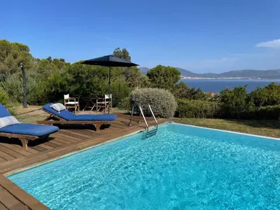 a swimming pool with two chairs and an umbrella at Villa L'usciata in Pietrosella