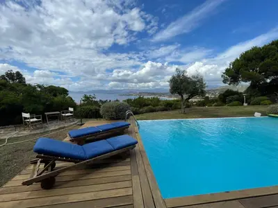 a pool with two blue lounge chairs on a wooden deck at Villa L'usciata in Pietrosella