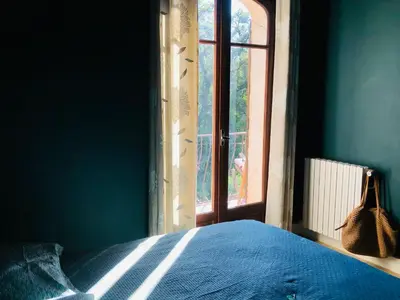 a bedroom with a blue bed and a window at Casa Scaglione in Porticcio