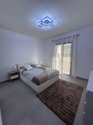 a white bedroom with a large bed and a window at Bel Appartement F3 proche de la plage in Pietrosella