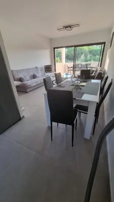 a dining room and living room with a table and chairs at Bel Appartement F3 proche de la plage in Pietrosella