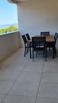a table and chairs on a balcony with a view of the ocean at Bel Appartement F3 proche de la plage in Pietrosella