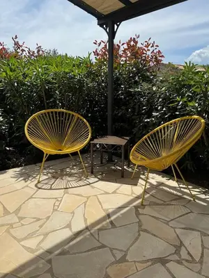 two yellow chairs and a table under an umbrella at Résidence Patios di Pruno in Figari