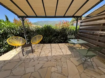 a patio with two chairs and a table and a bench at Résidence Patios di Pruno in Figari