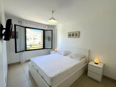 a white bedroom with a bed and a window at Joli T2 idéalement situé in Propriano