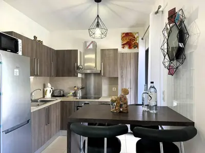 a kitchen with a table with chairs and a refrigerator at Joli T2 idéalement situé in Propriano