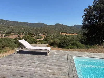 a white chair sitting on a deck next to a swimming pool at Entre mer et maquis- maison avec piscine privée - 8 minutes plage tizzano in Sartène