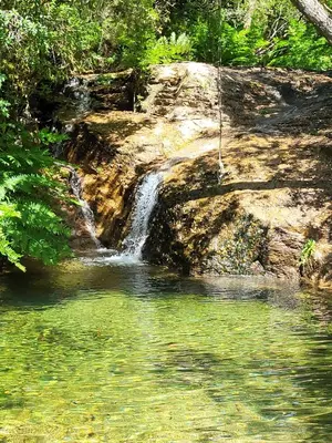 a waterfall next to a body of water at Porticcio - Agosta Plage - T2 - Chez Cath et JC in Albitreccia