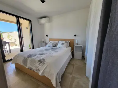 a bedroom with a bed and a large window at Porticcio - Agosta Plage - T2 - Chez Cath et JC in Albitreccia