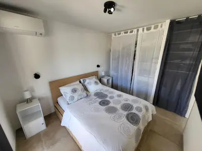 a bedroom with a bed with white sheets and pillows at Porticcio - Agosta Plage - T2 - Chez Cath et JC in Albitreccia