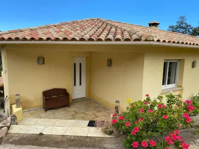 a small yellow house with a door and pink flowers at Les arbousiers de Murateddu in Porto-Vecchio