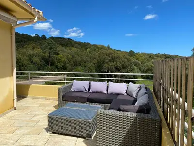 a wicker couch sitting on the balcony of a house at Les arbousiers de Murateddu in Porto-Vecchio