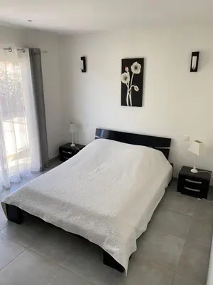 a bedroom with a large white bed with two lamps at Les arbousiers de Murateddu in Porto-Vecchio