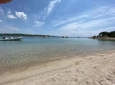 a boat in the water next to a beach at Casa di leo in Figari