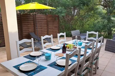 a white table with chairs and a yellow umbrella at Casa di leo in Figari