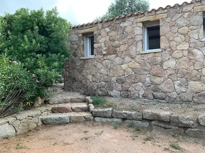 a stone building with a stone wall and two windows at La campagne au bord de la mer in Porto-Vecchio