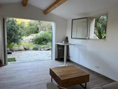 a living room with a table and a large window at La campagne au bord de la mer in Porto-Vecchio