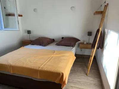 a bedroom with a bed with a ladder next to it at La campagne au bord de la mer in Porto-Vecchio