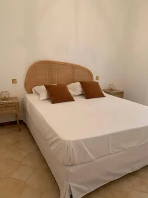 a large bed with white sheets and brown pillows at Appartement spacieux avec vue mer in Piana
