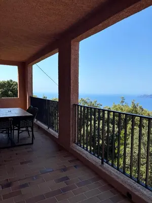 a balcony with a table and views of the ocean at Appartement spacieux avec vue mer in Piana