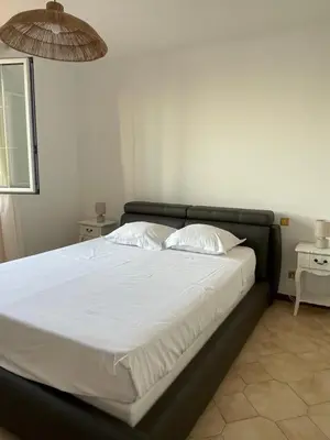 a bed with white sheets and pillows in a bedroom at Appartement spacieux avec vue mer in Piana
