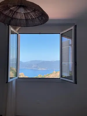 a room with two windows with a view of the ocean at Appartement spacieux avec vue mer in Piana