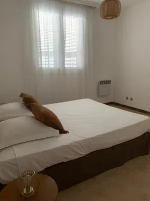a white bedroom with a large bed with a pillow on it at Appartement spacieux avec vue mer in Piana