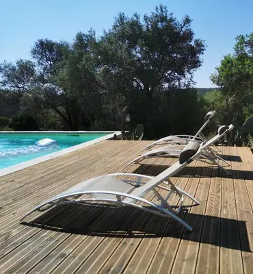 two lawn chairs sitting on a deck next to a swimming pool at U caseddu di Monacia in Monacia-dʼAullène