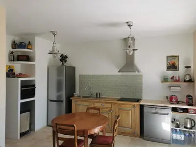 a kitchen with a table and a stainless steel refrigerator at U caseddu di Monacia in Monacia-dʼAullène