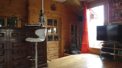 a living room with a chair and a television in a cabin at chalet 4 à 6 pers à la campagne 15 mn plages et Ajaccio grand terrain arboré calme assuré in Afa
