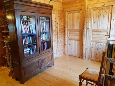 a room with a large wooden cabinet filled with books at chalet 4 à 6 pers à la campagne 15 mn plages et Ajaccio grand terrain arboré calme assuré in Afa