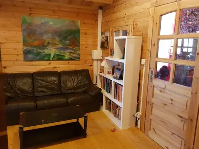 a living room with a leather couch and a book shelf at chalet 4 à 6 pers à la campagne 15 mn plages et Ajaccio grand terrain arboré calme assuré in Afa