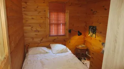 a bedroom with a bed in a wooden cabin at chalet 4 à 6 pers à la campagne 15 mn plages et Ajaccio grand terrain arboré calme assuré in Afa