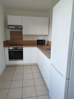 a kitchen with white cabinets and a tile floor at Appartement traversant 2 chambres in Ajaccio