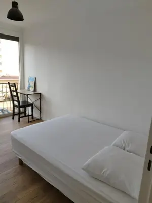a white bed in a room with a table at Appartement traversant 2 chambres in Ajaccio