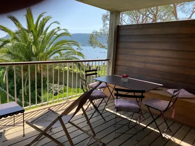 a table and chairs on a deck with a view of the water at Les oliviers 6 - Appartement pieds dans l'eau in Porto-Vecchio