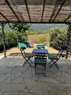 a patio with a table and chairs under a roof at Résidence Patios di Pruno in Figari
