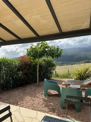 a patio with a table and chairs under a roof at Résidence Patios di Pruno in Figari