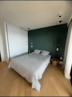 a bedroom with a white bed with a green wall at T4 standing a Cargese in Cargèse
