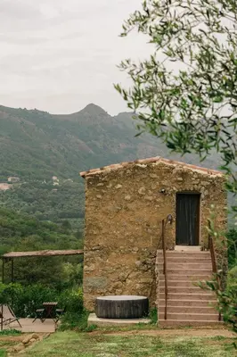a small stone building with a wheel in front of it at Domaine Acciola in Feliceto