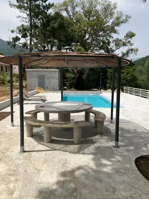 a picnic table in a pavilion next to a pool at A SUARELLA - Villa climatisée - 4 chambres - piscine chauffée in Sainte-Lucie de Porto-Vecchio