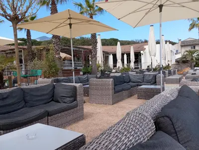 a patio with couches and umbrellas at belles chambres toutes équipées bord de mer gérance nouvelle in San-Nicolao