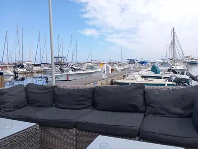 a couch sitting on top of a dock with boats at belles chambres toutes équipées bord de mer gérance nouvelle in San-Nicolao