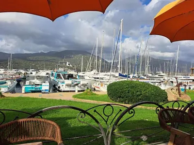 a bench with an umbrella and a marina with boats at belles chambres toutes équipées bord de mer gérance nouvelle in San-Nicolao