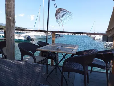 a table and chairs on a deck near the water at belles chambres toutes équipées bord de mer gérance nouvelle in San-Nicolao