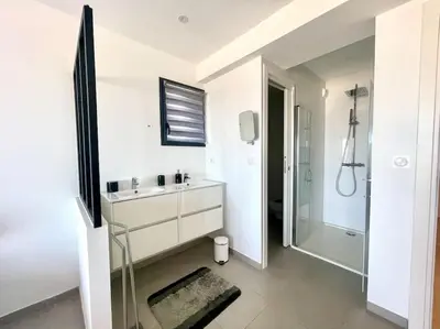 a white bathroom with a sink and a shower at Villa Pietrosella, vue sur la baie d'Ajaccio in Agnarelu