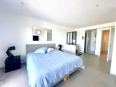 a bedroom with a large bed with a blue comforter at Villa Pietrosella, vue sur la baie d'Ajaccio in Agnarelu