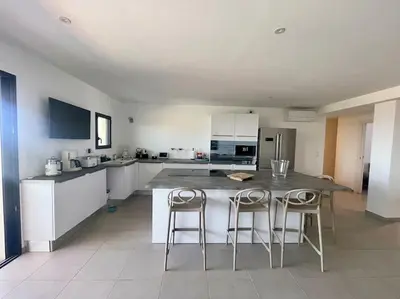 a kitchen with a table and two bar stools at Villa Pietrosella, vue sur la baie d'Ajaccio in Agnarelu