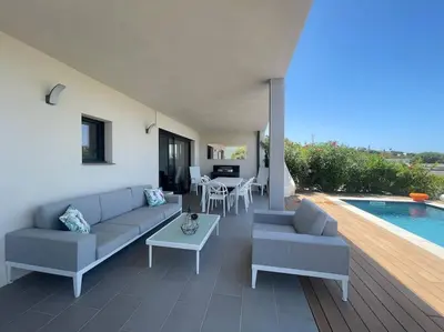 a living room with a couch and a table and a pool at Villa Pietrosella, vue sur la baie d'Ajaccio in Agnarelu