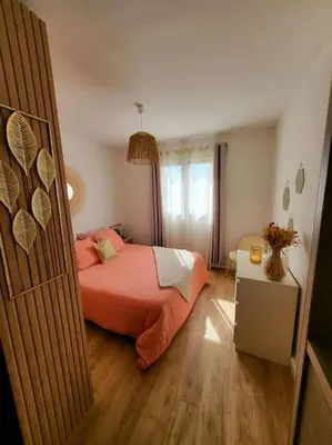 a bedroom with a bed with orange sheets and a window at Comme à la maison in Sarrola-Carcopino